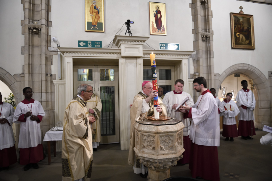 Bishop Marcus dips the paschal candle into the baptismal font thus blessing the water.